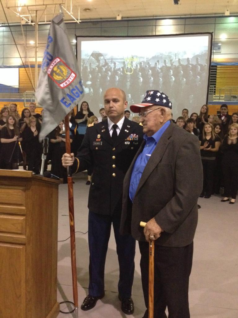 LOCAL HONOREE-- WWII veteran and POW Athel McClure was honored by Lt. Col. Jason Caldwell (left) at todays Veterans Day ceremony. Caldwell is pictured above holding JROTCs new guidon. The cedar pole was handmade by McClure, and it contains seven marbles near the top which represent the seven Army values.
