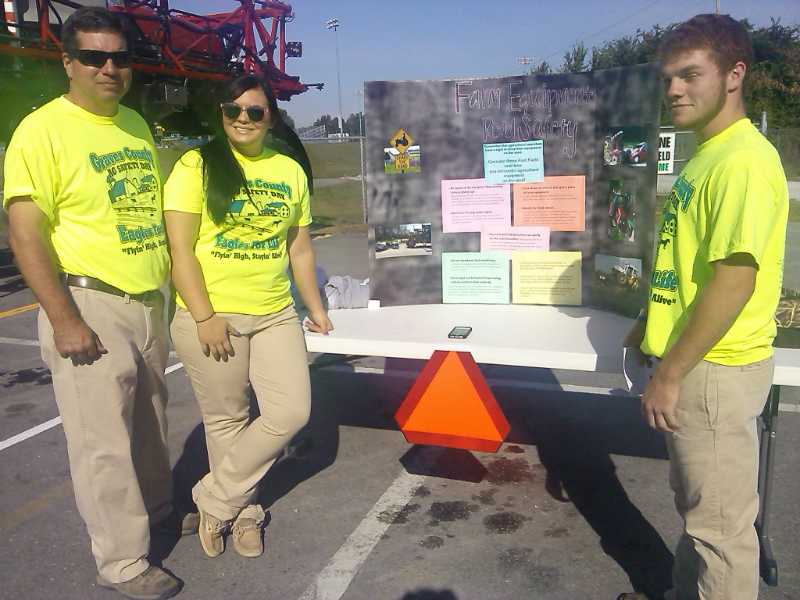 ROAD SAFETY-- Community volunteer Scott Wilferd helps seniors Savannah Leon and Isaac Darnell at their display concerning farm equipment on the road.