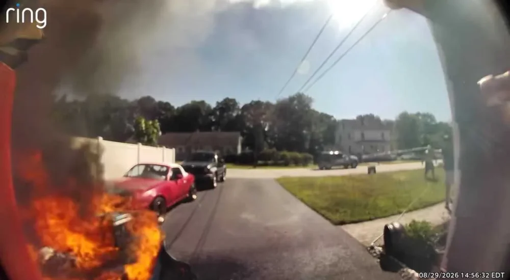 A Nashua neighbor uses a garden hose to help put out a garage fire at a home